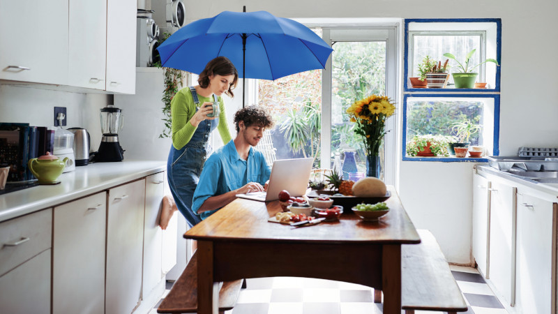 Imagebild junges Paar zusammen in der Küche an einem Laptop unter einem blauen Schirm